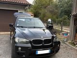 un SUV BMW noir garé devant un garage