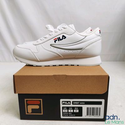un gros plan sur une paire de baskets blanches posées sur une boîte