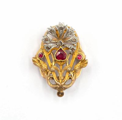 une image représentant une broche en or ornée de pierres rouges et de feuilles