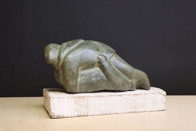 statue of a person laying on a block on a table