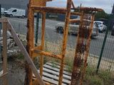 une cage métallique rouillée posée sur une palette dans un parking