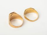 two gold rings on a white surface with a white background