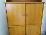 a tall wooden cabinet with two doors and a drawer