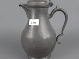 an old silver pitcher with a handle and a tag on it