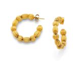 un gros plan sur une paire de boucles d'oreilles créoles en or sur fond blanc