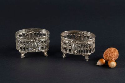 pair of silver plated bowls with acorns and nuts on a black background