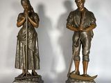 paire de statues en bronze représentant un homme et une femme, l'un tenant une canne