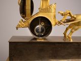 a gold clock with a horse pulling a carriage