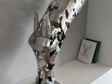 a silver sculpture on a white shelf in a room
