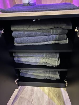 Les serviettes sont empilées sur une étagère dans une salle de bains, à côté d'un miroir