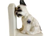 statue d'un chien assis au sommet d'une bibliothèque blanche