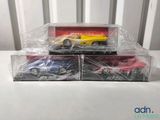 three toy cars in plastic boxes sitting on a table