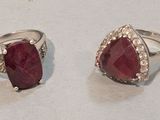 une paire de bagues en rubis et diamants posées sur un fond blanc