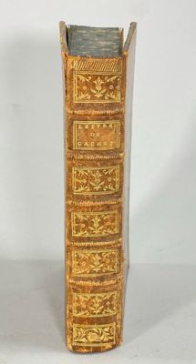 un vieux livre posé sur une table à côté d'un mur blanc