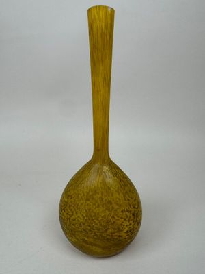 un vase jaune posé sur une surface blanche