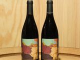 deux bouteilles de vin posées sur un tonneau en bois