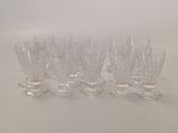 six clear glass goblets lined up on a white surface