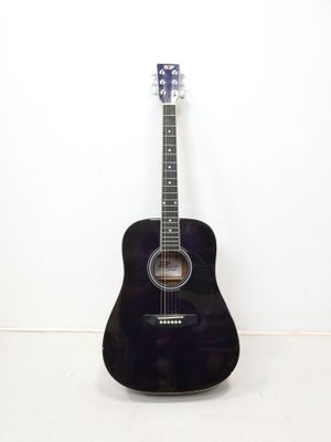 une photo d'une guitare acoustique noire posée contre un mur blanc