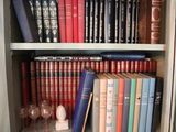 a book shelf with many books and wine glasses on it