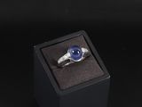une photo d'une bague dans un écrin, ornée d'une pierre bleue