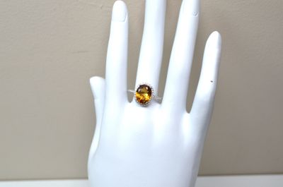 une main à laquelle est passée une bague sertie d'une citrine