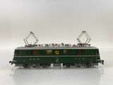 a green train that is on the tracks on a white surface