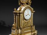 a gold and white clock on a stand on a black background