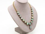 a close up of a necklace on a mannequin with a white background