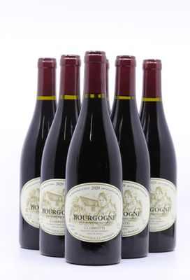 quatre bouteilles de vin rouge sont alignées sur une surface blanche