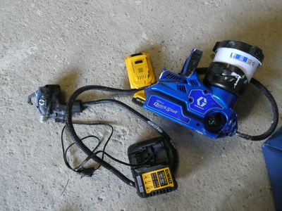 une photo d'une perceuse électrique bleue et jaune et d'autres outils posés par terre