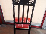 a black chair with a red cushion in front of a glass door