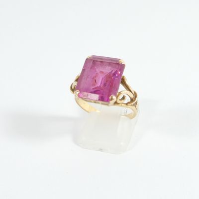 gros plan d'une bague en pierre rose sur une surface blanche