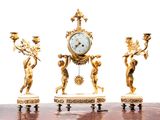 three gold statues of cherenshes and a clock on a table
