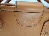 a close up of a brown leather bag with a tag on it