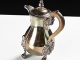 a silver pitcher sitting on a table with a black background