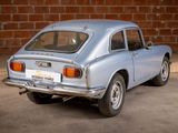 a silver car parked in front of a brick wall
