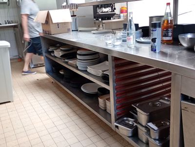 un homme debout dans une cuisine, avec beaucoup de vaisselle sur le plan de travail
