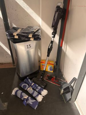 a trash can, broom, mop, and other cleaning supplies on the floor