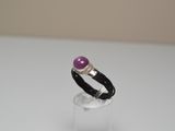 bague en argent ornée d'une pierre violette posée sur du verre transparent