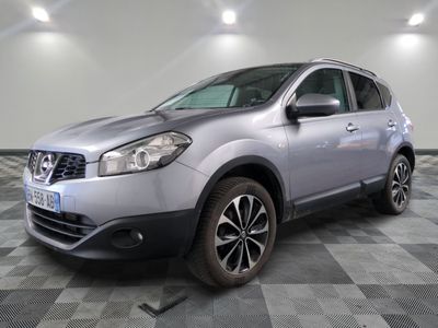 La Nissan QX-V argentée est garée sur un sol en carrelage à damier.