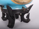 a blue vase with a gold fish on it on a stand