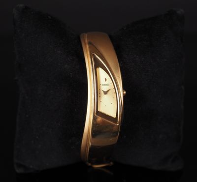 a close up of a gold wrist watch on a black pillow