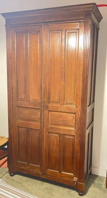 a wooden armoire in the corner of a room