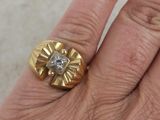 a person ' s hand holding a gold ring with a diamond