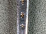 a silver spoon with writing on it sitting on a leather surface