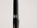 a close up of a pen on a white surface with a shadow