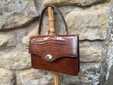 a brown purse that is hanging on a wooden pole