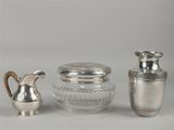 deux vases en argent et un bocal en verre posés sur une table