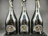 trois bouteilles de champagne posées sur une boîte noire