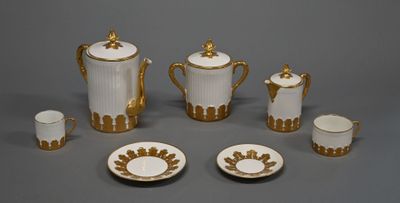 an image of a white and gold tea set with cups and saucers